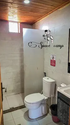 a bathroom with a toilet and a sign on the wall at Wadi Rum Space camp in Wadi Rum