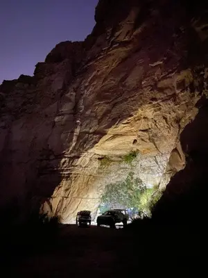 a car parked in front of a rocky mountain at Fog Mountain Hotel Rooms & sauna in Jaḩrāʼ