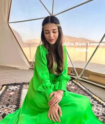 a woman in a green dress sitting under an umbrella at JULIA RUM lUXURY CAMP in Wadi Rum