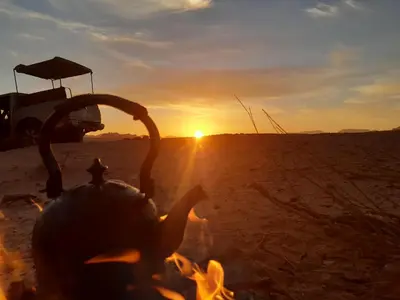 a fire in the desert with the sunset in the background at Mad Mix camp in Wadi Rum