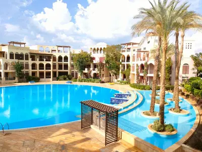 a large swimming pool with palm trees and buildings at one bedroom apartments aqaba on for family only 2 swimming pool Tala bay for family only in Aqaba