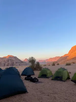 a group of four tents in the desert at Desert Jewel Camp in Wadi Rum