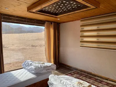 a bedroom with a window with a view of the desert at Desert Jewel Camp in Wadi Rum
