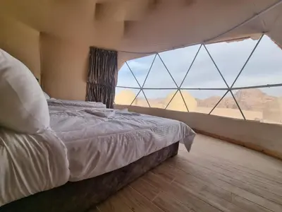 a bedroom with a bed and a large window at Desert Jewel Camp in Wadi Rum