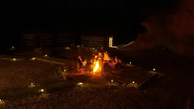 a group of people around a fire at night at Desert Jewel Camp in Wadi Rum