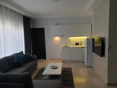 a living room with a couch and a kitchen at Deir Ghbar-Studio in Amman