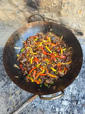a wok filled with meat and peppers on top at Petraone in Wadi Musa