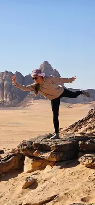 a woman standing on a rock in the desert at Ammar Rum Camp and tours in Wadi Rum
