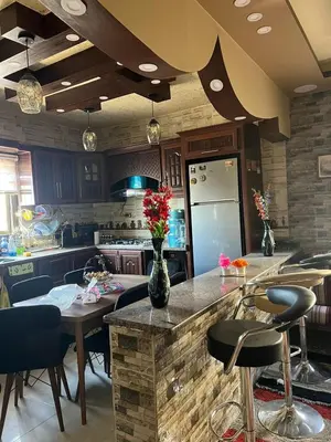 a kitchen with a counter with chairs and a table with flowers at Beida Bedouin House in Al Ḩayy