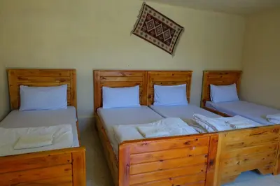 two twin beds in a room with wooden furniture at Dana Nabil Ecu Camp House - Main Gate Dana nature reserve in Dana