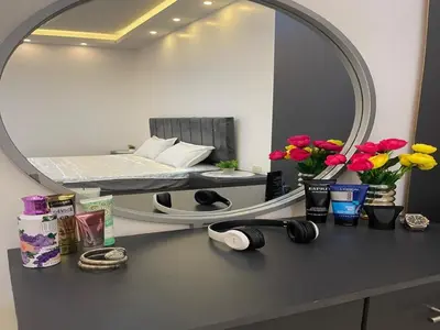 a mirror on a desk with flowers and a bed at Aroma Chalet in Sowayma
