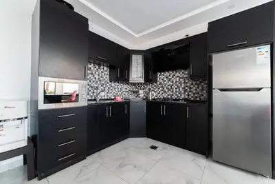 a kitchen with black cabinets and a stainless steel refrigerator at Aroma Chalet in Sowayma