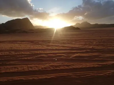 a sunset in the desert with mountains in the background at The calm nature of Wadi Rum in Wadi Rum