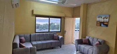 a living room with two couches and a large window at العاصم للشقق الفندقية ALASEM HOTEL APARTMENTS in Aqaba