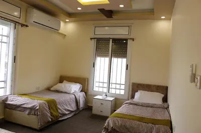 two beds in a room with two windows at Petra Mountain House in Wadi Musa