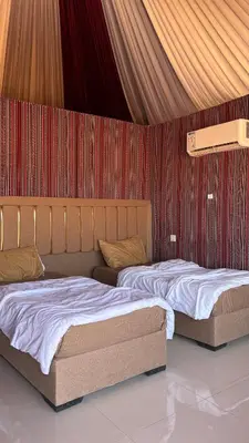 two beds in a room with a red wall at altair luxury rum in Wadi Rum
