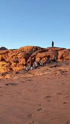 a group of people sitting on top of a cliff at altair luxury rum in Wadi Rum