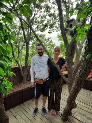 a man and a woman standing next to a tree at Green House in Zūbiyā