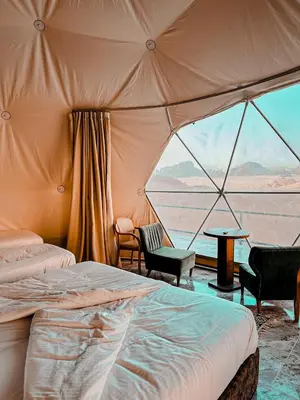 a tent with a bed and chairs and a table at rum fun luxury camp in Wadi Rum