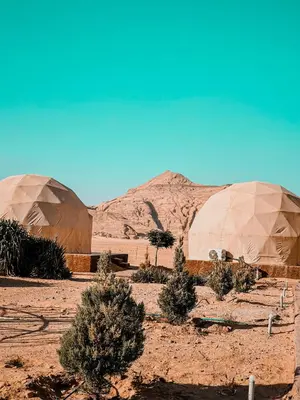 two domes in the desert with trees and mountains at rum fun luxury camp in Wadi Rum