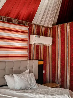 a bedroom with a bed with a red wall at rum fun luxury camp in Wadi Rum