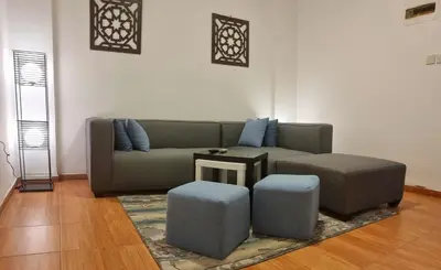 a living room with a couch and two stools at Byblos Aqaba in Aqaba