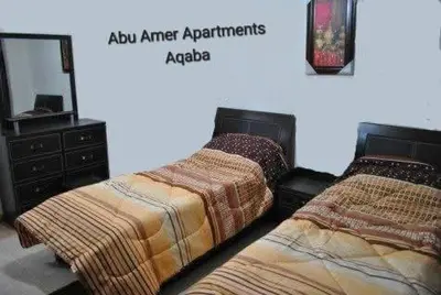 a bedroom with two beds with a dresser and a mirror at Abo Amer Apartments in Aqaba