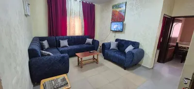 a living room with two blue couches and a table at Abo Amer Apartments in Aqaba