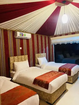 a bedroom with three beds and a tent at WADi RUM LUXURY RITZ in Wadi Rum