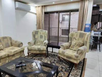 a living room with two chairs and a table at Dream Home in Amman