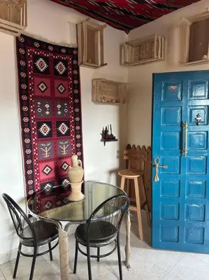 a dining room with a glass table and two blue doors at Antica old apartment al-lwebdeh in Amman
