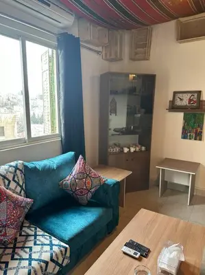 a living room with a blue couch and a table at Antica old apartment al-lwebdeh in Amman
