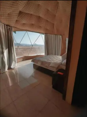 a bedroom with a bed and a large window at RUM ARJAAN lUXURY CAMP in Wadi Rum