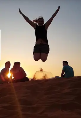 a woman jumping in the air in the desert at RUM ARJAAN lUXURY CAMP in Wadi Rum