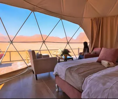 a woman sitting in a tent with a view of the desert at RUM ARJAAN lUXURY CAMP in Wadi Rum