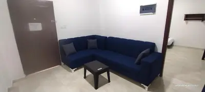 a blue couch in a room with a table at Happy Beach For Studio Rooms Apartment شاطئ السعادة للشقق المفروشة in Aqaba
