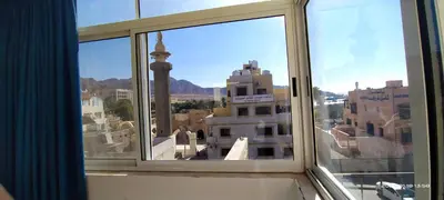 a window with a view of a city at Happy Beach For Studio Rooms Apartment شاطئ السعادة للشقق المفروشة in Aqaba