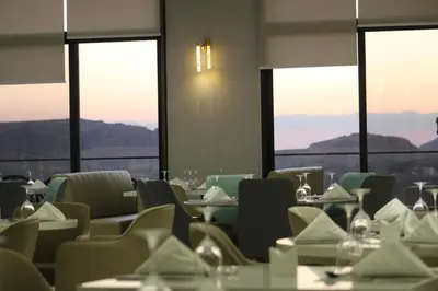 a dining room with tables and chairs and windows at H Luxury Hotel in Wadi Musa
