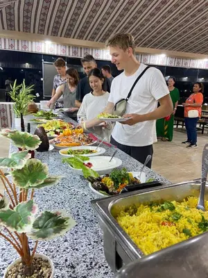 a man standing in front of a buffet line with food at Adel Wadi Rum Camp Bubble in Wadi Rum