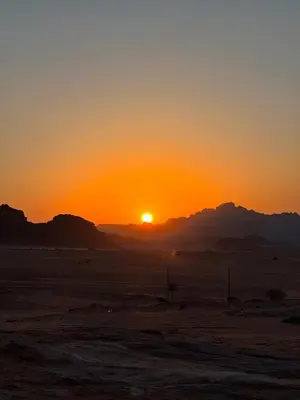 a sunset in the desert with mountains in the background at Wadi Rum stael Luxury Camp in Wadi Rum