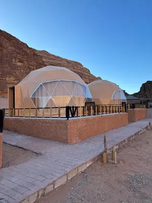 two domed buildings with people walking under them at Wadi Rum stael Luxury Camp in Wadi Rum