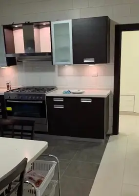 a kitchen with black cabinets and a stove at Amman Business Park Apartment in Amman