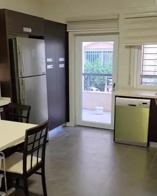 a kitchen with a refrigerator and a table and a window at Amman Business Park Apartment in Amman