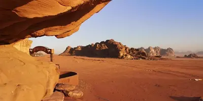a view of a desert with rocks in the background at wadi rum Golden Sand in Wadi Rum
