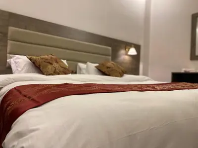 a bedroom with a large white bed with two pillows at Petra Oleander Hotel in Wadi Musa