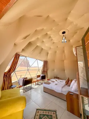 a bedroom with a bed and a large window at Mira Bubble Luxury Camp in Wadi Rum