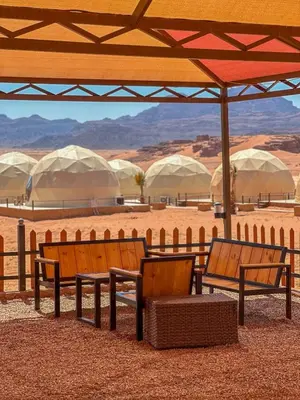two benches sitting under an umbrella in the desert at Mira Bubble Luxury Camp in Wadi Rum