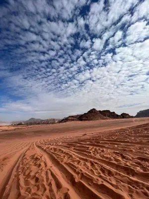 a sandy desert with a blue sky and clouds at Mira Bubble Luxury Camp in Wadi Rum