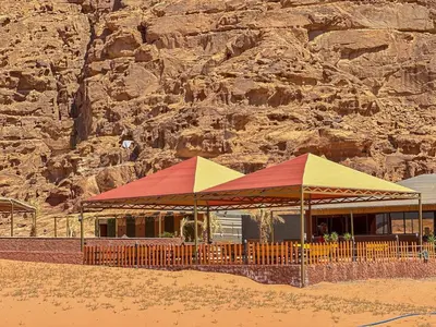 a building with red and yellow umbrellas on the beach at Mira Bubble Luxury Camp in Wadi Rum