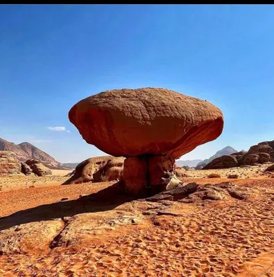 a large rockolith in the middle of a desert at غرووب وادي رم in Wadi Rum